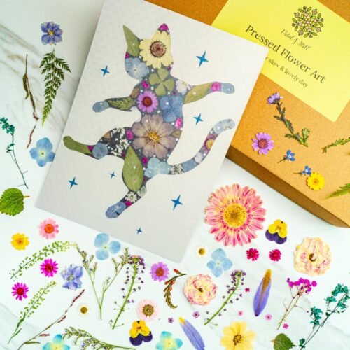 Colorful pressed flower art featuring a whimsical cat silhouette filled with vibrant flower arrangements, perfect for floral wall decor and botanical art projects.