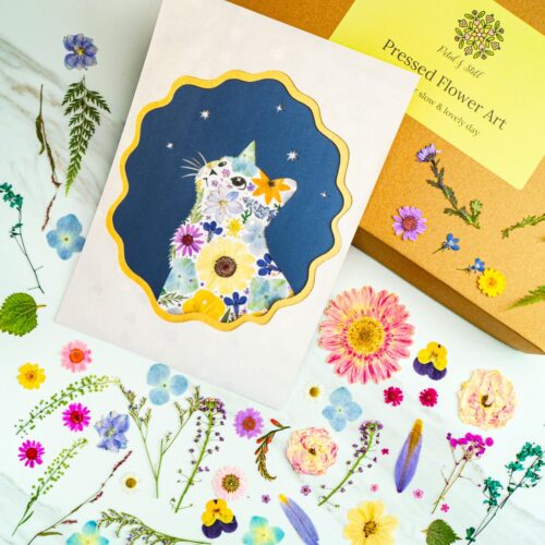 Pressed flower art print featuring a floral cat design with colorful, preserved flowers on a dark blue background. Perfect for botanical decor and nature-inspired wall art.