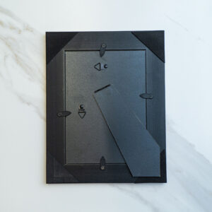 Modern black mail or key storage box with security lock, mounted on a white marble wall, emphasizing contemporary design and functional home security.