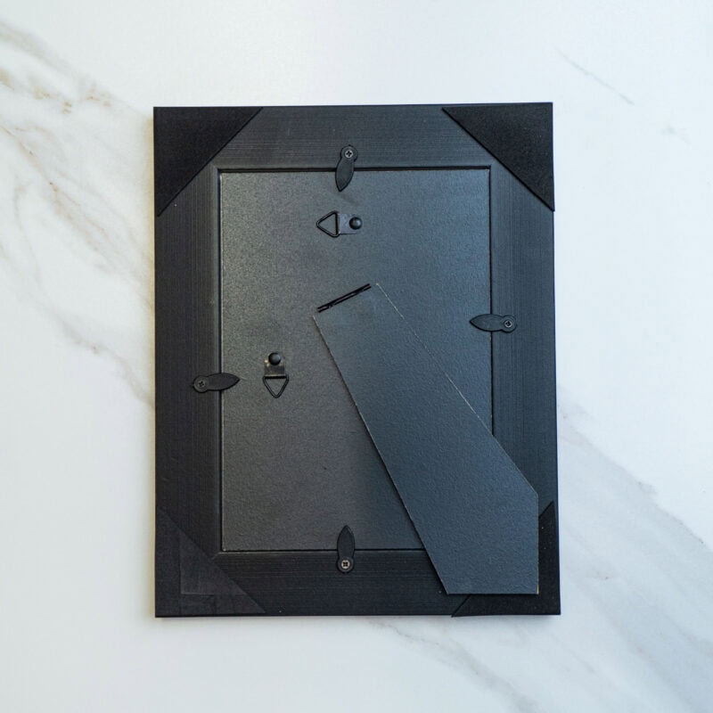 Modern black mail or key storage box with security lock, mounted on a white marble wall, emphasizing contemporary design and functional home security.